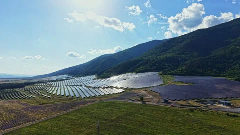 Solar panels cover a large area on hills under sunlight with clouds above in a Stock Footage 340772811