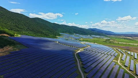 Solar panels cover a large area near a mountain under a clear sky with some Stock Footage 341606112