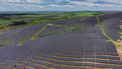 Solar panels cover a large field in a green landscape under blue sky Stock Footage 339019621