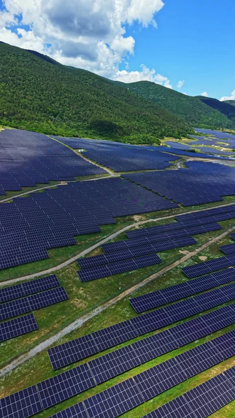 Solar panels cover a large field in a hilly area with blue sky and fluffy clouds Stock Footage 340870464