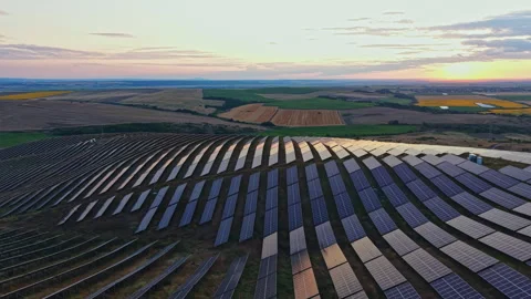 Solar panels cover a large field in a rural area during sunset showcasing Stock Footage 340932158