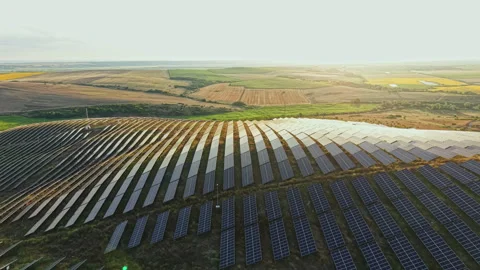 Solar panels cover large fields in a rural area during late afternoon with sun Stock Footage 340933474