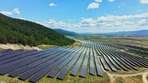 Solar panels cover large fields under blue sky with scattered clouds in a rural Stock Footage 341132826