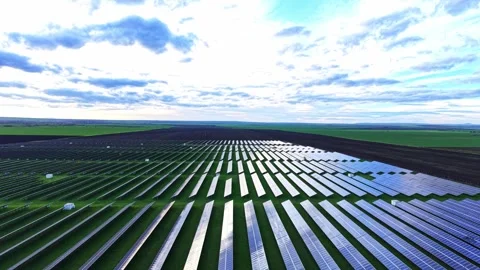 Solar panels cover vast fields under a cloudy sky in a rural area Stock Footage 325090483