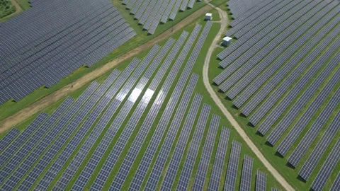 Solar panels installed on uneven meadow terrain surrounded by forest Stock Footage 314377363