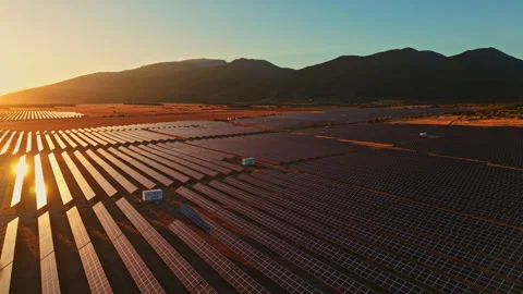 Solar panels in a large field during sunset near mountains in the background Stock Footage 347768773