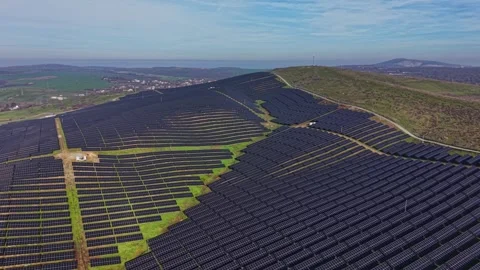 Solar panels in a large field on a hillside under a clear sky 库存影片 329998786