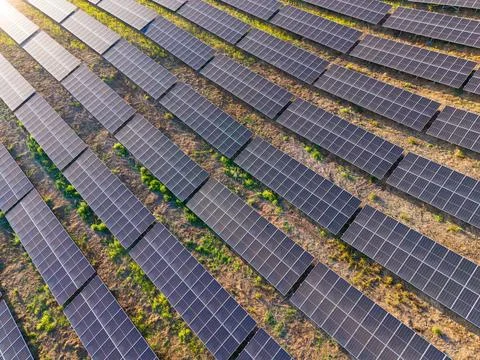 Solar panels in a large field at sunset with sun rays shining over the arra.. Stock Photos