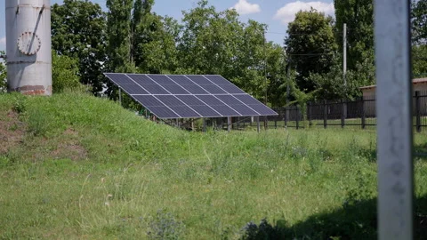 Solar panels positioned on a grassy hill, capturing sunlight in a lush green Stock Footage 319529779