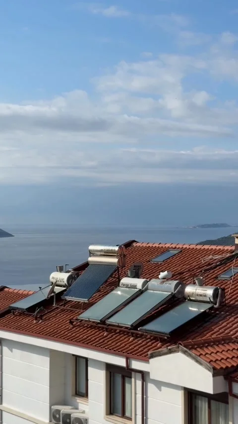 Solar panels on red tile rooftop overlooking sea and cloudy sky, sustainabl.. Stock Footage 336398468
