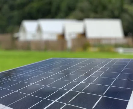 Solar panels set against a backdrop of resident, trees and a vibrant blue s.. Stock Photos