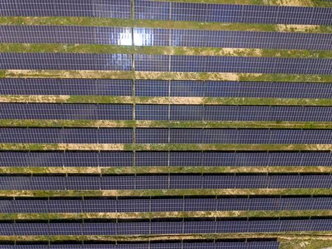 Solar panels sit in rows on a flat surface under bright sunlight in daytime Stock Photos