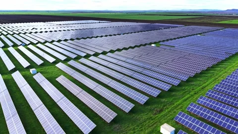 Solar panels spread across a vast green field in bright daylight Stock Footage 325088463