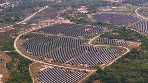 Solar power farm with curved rows of panels and surrounding greenery fields and 動画素材 309440145