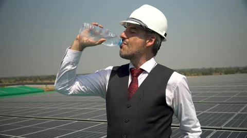 Solar power plant engineer in hard hat drinking water During  inspection phot Stock Footage 154285007