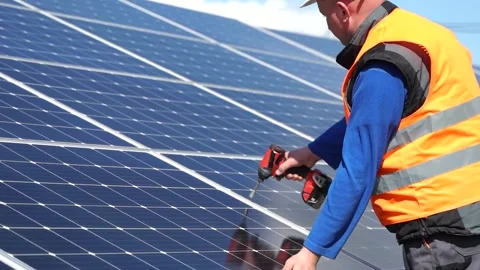 Solar power plant worker standing on a stepladder tightens solar panels Stock Footage 168178525