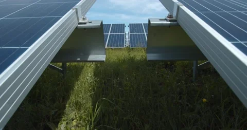 Solar power station, view in between two big solar panels, green grass, sky, 4k Stock Footage 134003249
