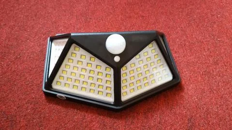 Solar-Powered Outdoor Motion Sensor LED Light on Red Background Stock Photos