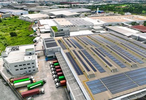 Solar-powered warehouse facility with freight trucks at loading docks. Eco-.. Stock-Fotos