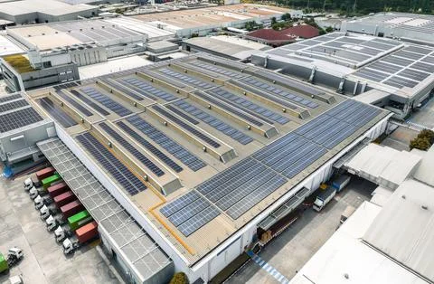 Solar-powered warehouse facility with freight trucks at loading docks. Eco-.. Stock-Fotos