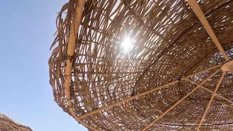 Solar rays shining through woven reed beach umbrella in Sinai Peninsula. Summer Stock Footage 330325062