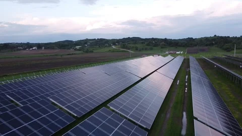 Solar Symphony: Drone Soaring Over Sunlit Solar Panel Field at Sunset Stock Footage 255524027
