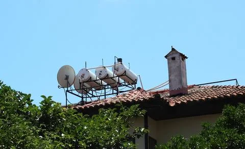 A solar water heating system is installed on the roof of a residential building. Stock Photos