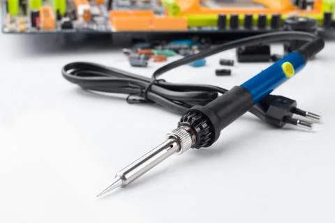 Soldering iron on the background of a computer Board and capacitors in soft f Stock Photos