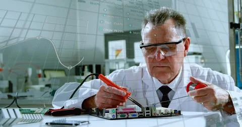 Soldering tech in lab coat leaning over motherboard at bench with orange iron Stock Photos