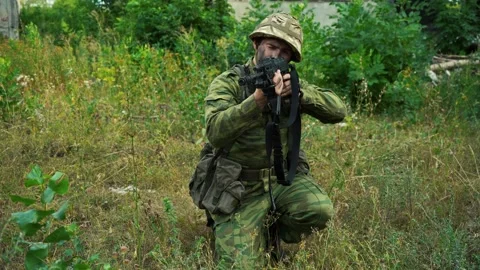 Soldier aiming from a machine gun while sitting in the woods Stock Footage 158892881