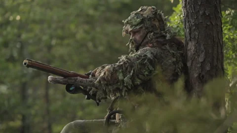 Soldier aims weapon while hiding in wilderness during a training exercise Stock Footage 327962336