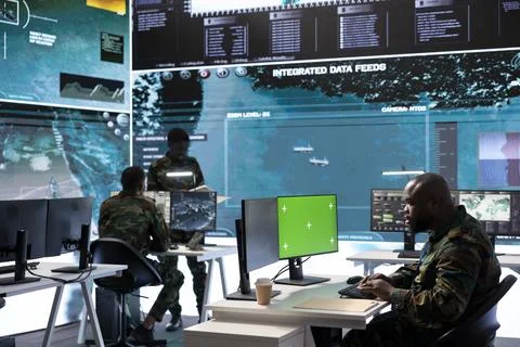 Soldier analyzing real time data next to green screen in high tech office Stock Photos