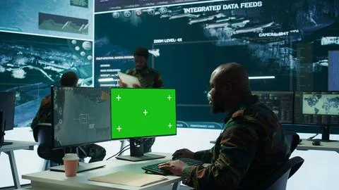 Soldier analyzing real time data next to green screen in high tech office Stock Photos