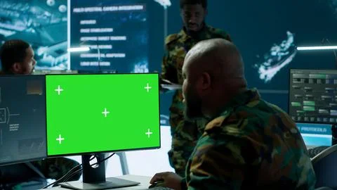 Soldier analyzing real time data next to green screen in high tech office Stock Photos
