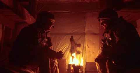 A soldier and a chaplain sit opposite each other in a dark dugout Stock Footage 263296544