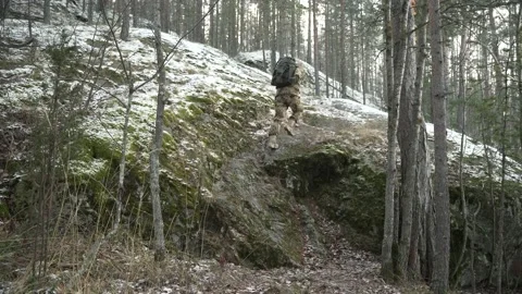 A soldier with a backpack running through the winter forest Stockbeeldmateriaal 230083833