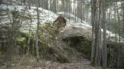 A soldier with a backpack running through the winter forest Видео 230083867