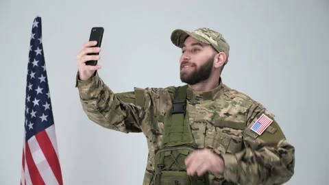 A soldier in a cap and backpack having video call with his family using phone. Stock Footage 146575999
