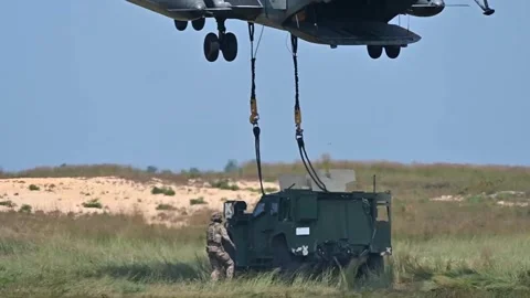 Soldier checking chains attached to JLTV prior to external lift by CH-53 Stock Footage 282248559