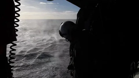Soldier closing door of helicopter while hovering above ocean Видео 122214355