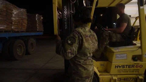 Soldier directs a forklift operator to remove pallets of US Aid Stock Footage 113344084