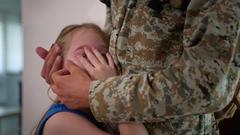 Soldier gently holding his daughter's head as they look at each other, 스톡 동영상 340337375