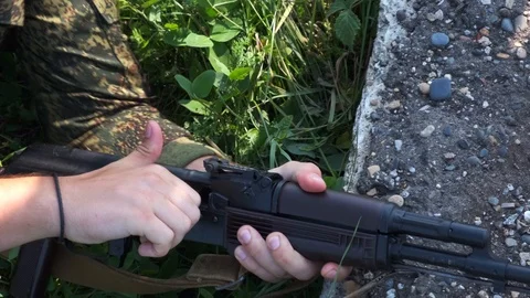 A soldier in the grass opens the shutter of the Kalashnikov AK-47 Stock Footage 118375649