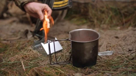 Soldier heating food using a small fire next to a rifle Stock Footage 114018713