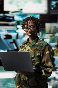 Soldier in high tech command center monitoring intelligence feed on laptop Stock Photos