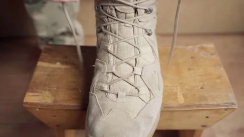 A soldier laces up a sand-colored boot, close-up Stock Footage 209914641