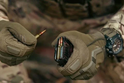 A soldier is loading cartridges into a machine gun magazine. Stock Photos