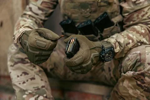 A soldier is loading cartridges into a machine gun magazine. Stock Photos