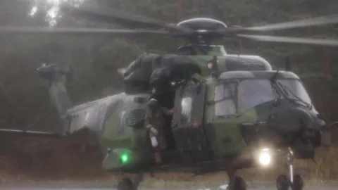 Soldier looking out from side door of Finnish NH90 helicopter during landing Stock Footage 283073317