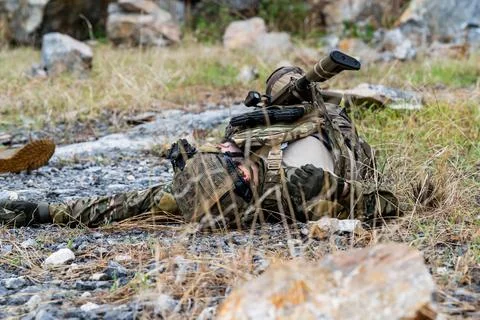 Soldier lying on ground during training exercise in rocky outdoor area Stock Photos